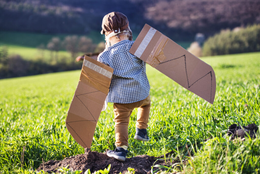 Little child trying to fly with homemade cardboard wings